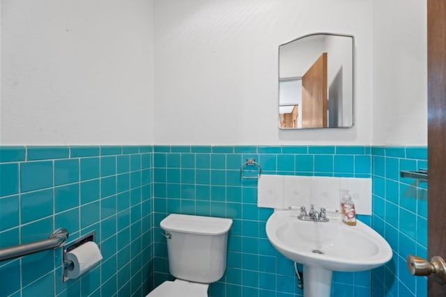 bathroom with toilet, sink, and tile walls