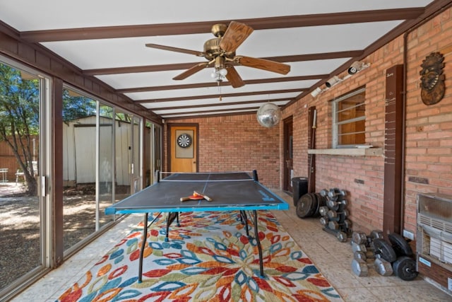 rec room with beamed ceiling, brick wall, and ceiling fan