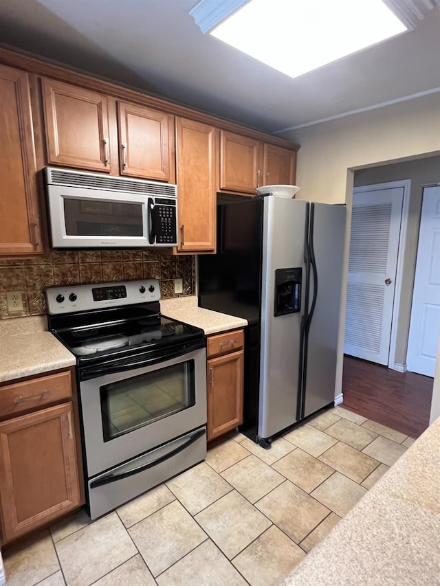 kitchen with tasteful backsplash, appliances with stainless steel finishes, and light tile patterned flooring