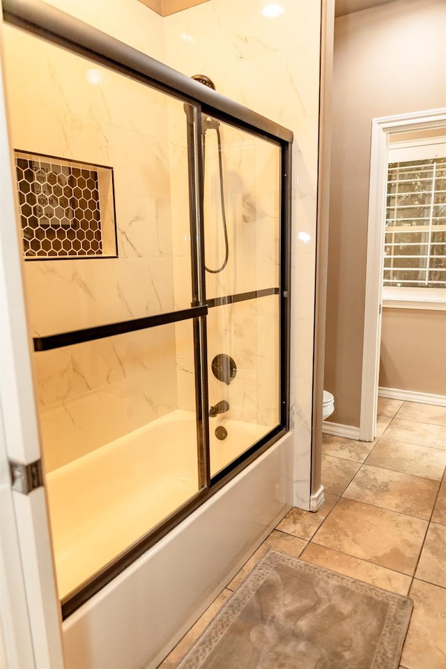 bathroom with toilet and combined bath / shower with glass door