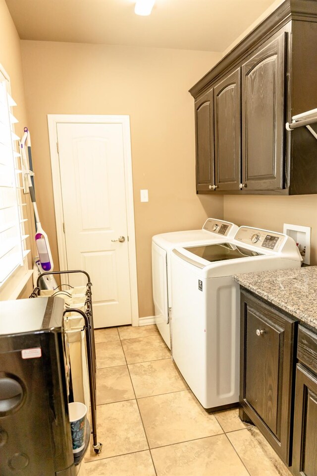 laundry area featuring light tile patterned floors, washing machine and dryer, and cabinets