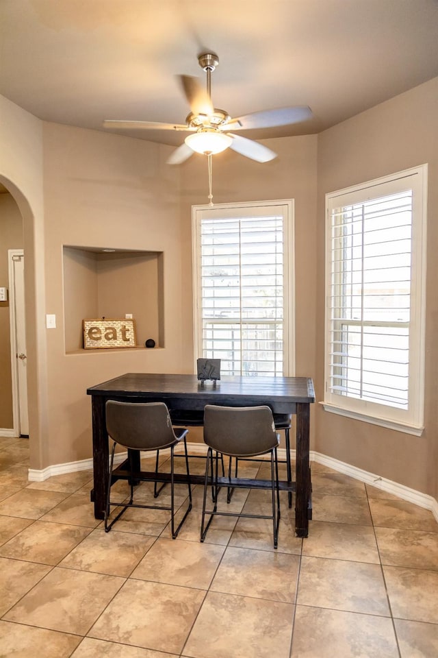 tiled dining space with ceiling fan and a healthy amount of sunlight