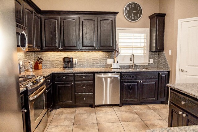 kitchen featuring light stone counters, dark brown cabinetry, appliances with stainless steel finishes, and sink