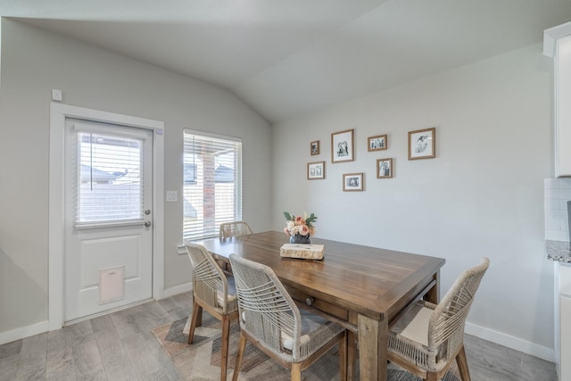 dining space featuring lofted ceiling and light hardwood / wood-style flooring