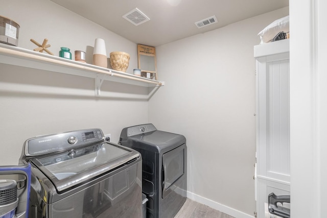 clothes washing area featuring light hardwood / wood-style floors and independent washer and dryer