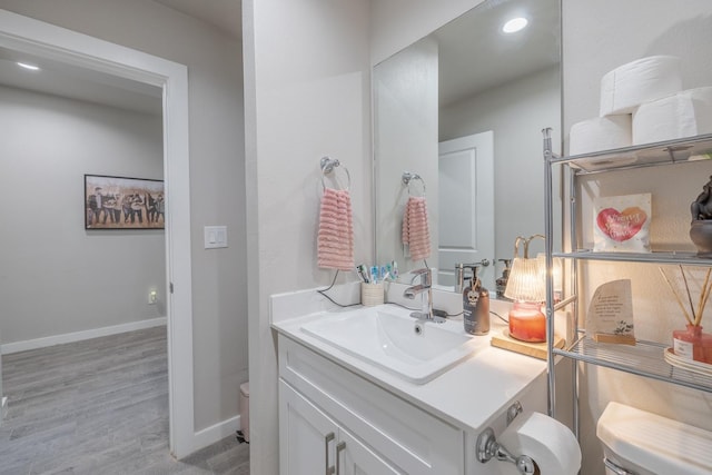 bathroom featuring vanity, wood-type flooring, and toilet