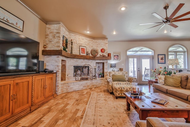 living room featuring ornamental molding, a stone fireplace, and a healthy amount of sunlight