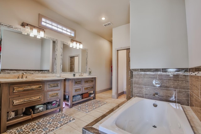 bathroom with tile patterned flooring, vanity, and tiled tub