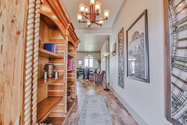 corridor with crown molding, wood-type flooring, and a notable chandelier