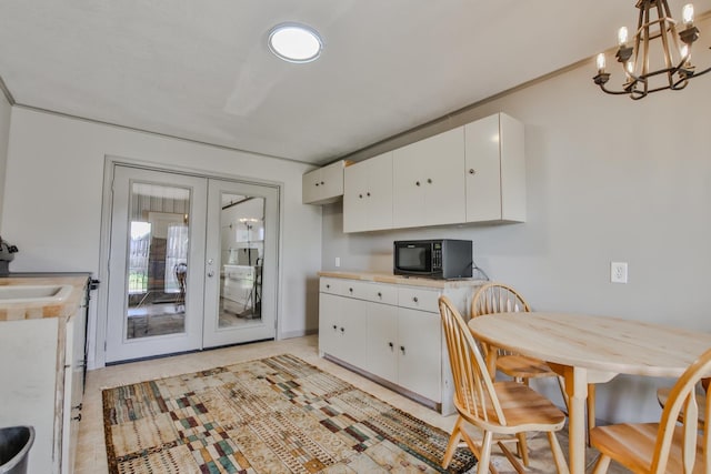 kitchen with white cabinetry, decorative light fixtures, french doors, and a chandelier