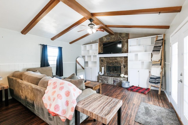 living room with lofted ceiling with beams, a stone fireplace, dark wood-type flooring, and ceiling fan