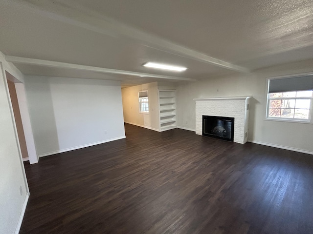 727 E 12th St, Littlefield, TX 79339 - unfurnished living room with dark wood-style flooring, a fireplace, and baseboards