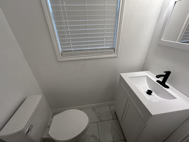 727 E 12th St, Littlefield, TX 79339 - bathroom featuring marble look tiles, vanity, toilet, and baseboards