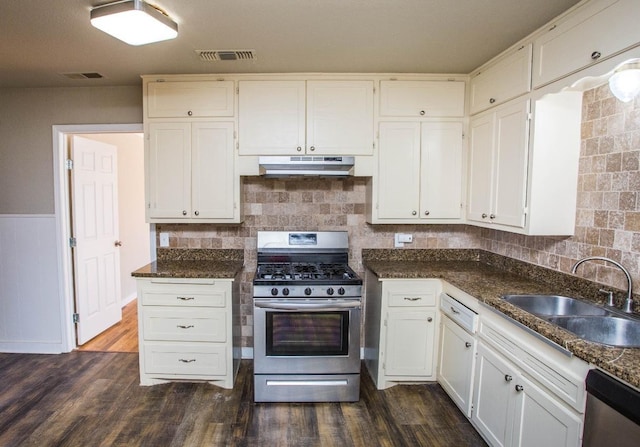 kitchen featuring sink, white cabinetry, appliances with stainless steel finishes, dark hardwood / wood-style flooring, and dark stone counters