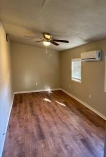 spare room with ceiling fan, dark hardwood / wood-style flooring, and a wall mounted AC