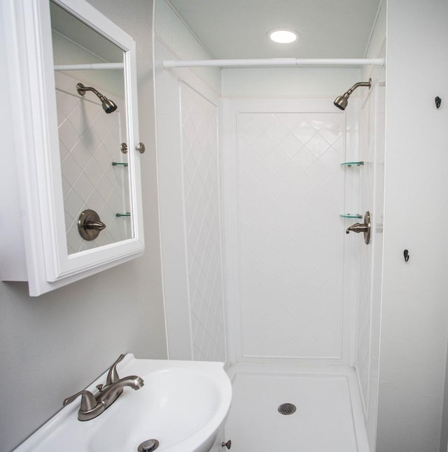 bathroom featuring a tile shower and sink