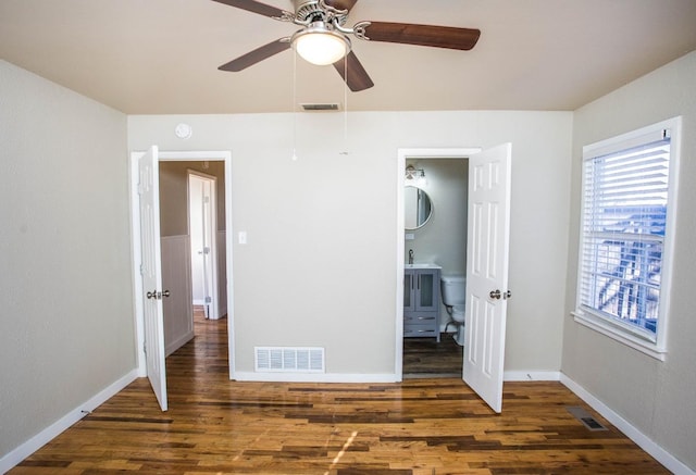 unfurnished bedroom with ensuite bathroom, dark hardwood / wood-style floors, and ceiling fan