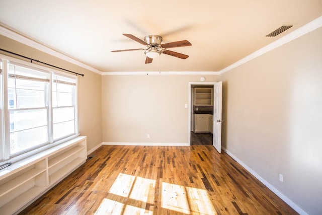 empty room featuring crown molding, dark wood-type flooring, and ceiling fan