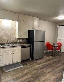 kitchen with sink, white cabinets, stainless steel appliances, a barn door, and dark wood-type flooring