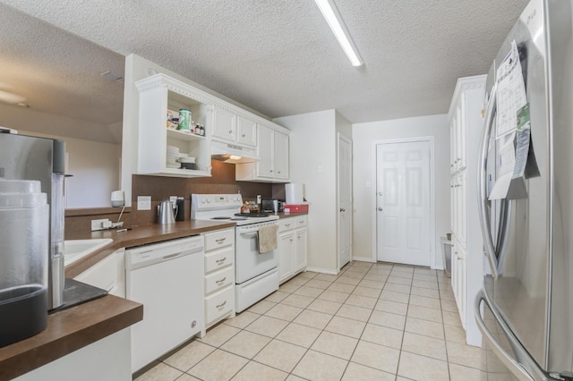 kitchen with light tile patterned floors, white appliances, wooden counters, a textured ceiling, and white cabinets