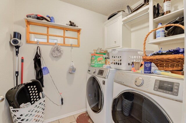 laundry area with cabinets, light tile patterned floors, a textured ceiling, and washing machine and clothes dryer