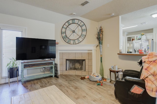 living room featuring hardwood / wood-style floors, a fireplace, and a textured ceiling