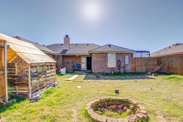 back of property with an outdoor fire pit and a lawn