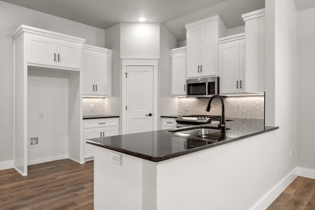 7814 96th St, Lubbock, TX 79424 - kitchen featuring stainless steel microwave, a sink, dark wood-type flooring, a peninsula, and baseboards