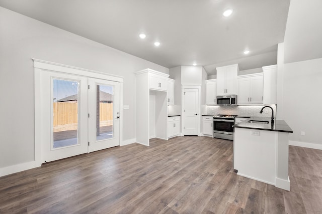 7814 96th St, Lubbock, TX 79424 - kitchen featuring stainless steel appliances, dark countertops, a sink, wood finished floors, and white cabinetry
