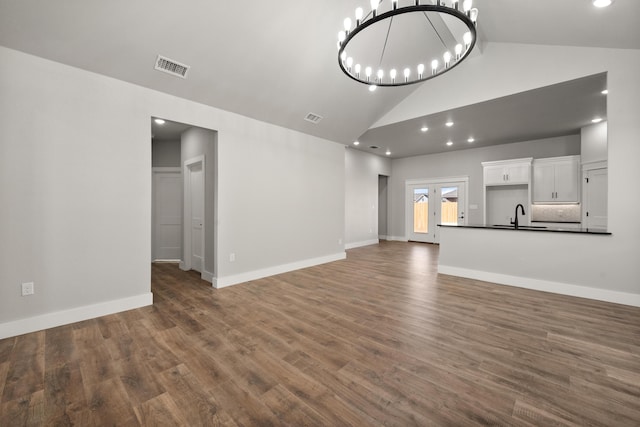 7814 96th St, Lubbock, TX 79424 - unfurnished living room featuring a sink, wood finished floors, a chandelier, high vaulted ceiling, and baseboards