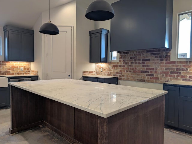 kitchen with pendant lighting, a kitchen island, decorative backsplash, and light stone countertops