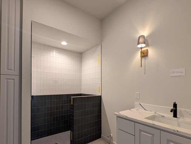 bathroom with a tile shower and vanity