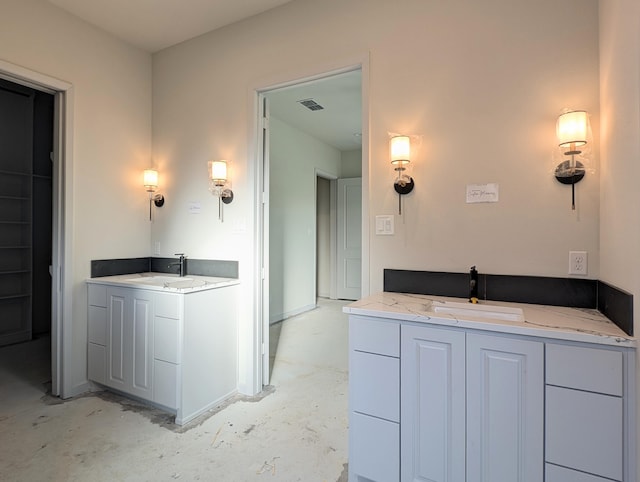 bathroom with unfinished concrete flooring, visible vents, two vanities, and a sink