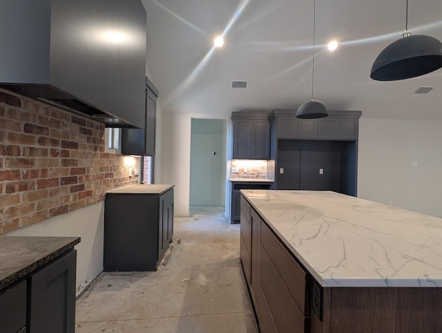 kitchen featuring light stone counters, visible vents, unfinished concrete flooring, and a kitchen island