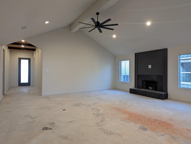 unfurnished living room featuring a tiled fireplace, vaulted ceiling with beams, a wealth of natural light, and ceiling fan