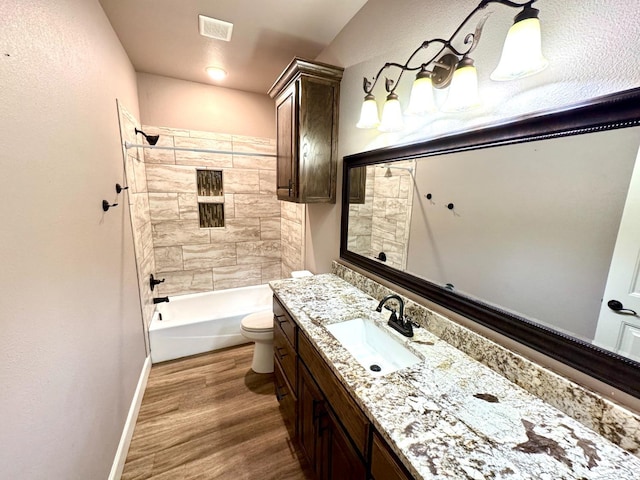 bathroom with vanity, toilet, bathing tub / shower combination, wood finished floors, and visible vents