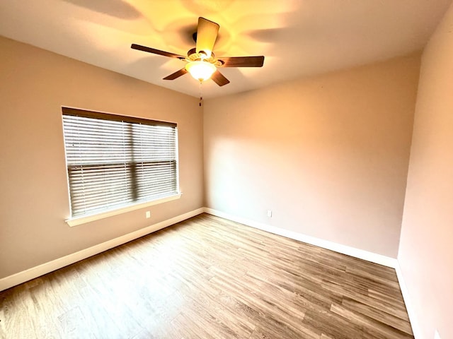 spare room with baseboards, ceiling fan, and wood finished floors