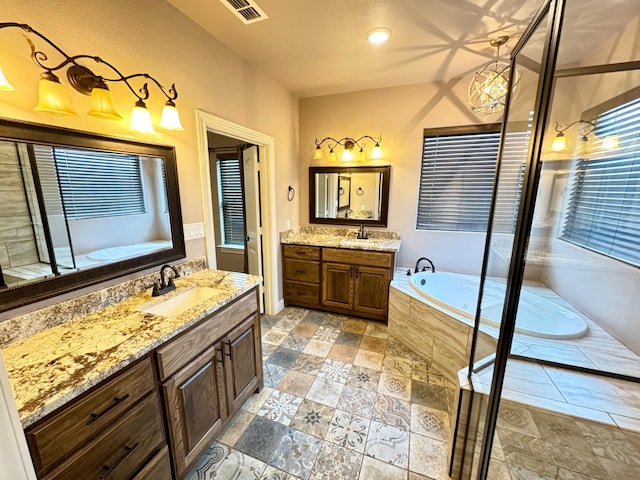 bathroom featuring stone tile floors, visible vents, two vanities, and a sink