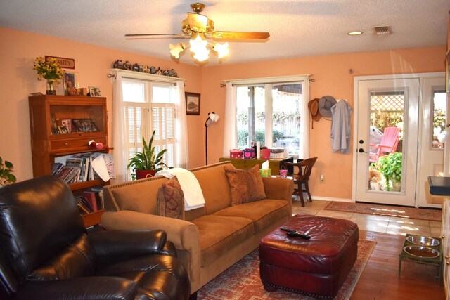 living room featuring ceiling fan, a textured ceiling, visible vents, and a wealth of natural light