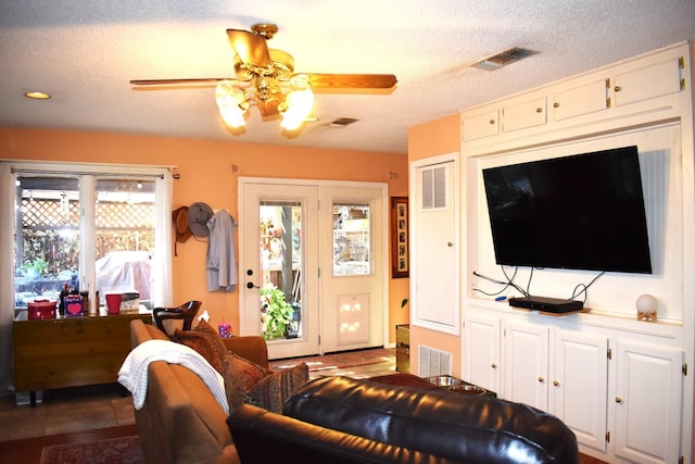 living room featuring a textured ceiling, ceiling fan, and visible vents