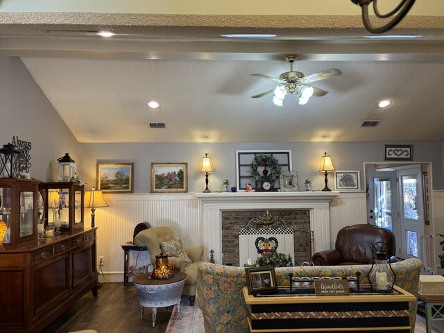 living room featuring vaulted ceiling with beams, a textured ceiling, a fireplace, and wood-type flooring