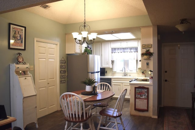 dining area featuring a chandelier, dark wood-type flooring, a textured ceiling, and visible vents