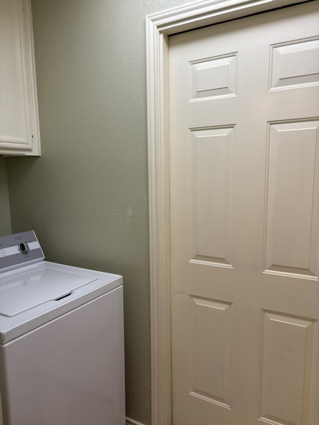 laundry area with washer / dryer, cabinet space, and a textured wall