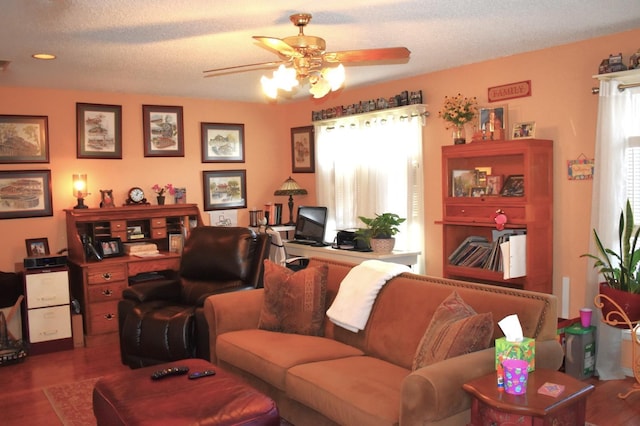 living room with a textured ceiling, visible vents, wood finished floors, and a ceiling fan