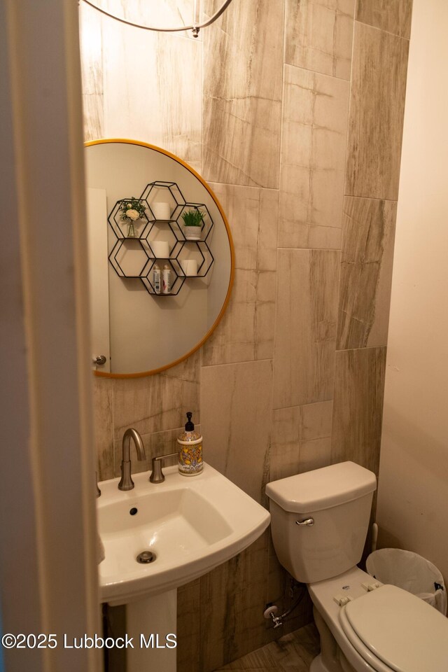 11707 Uxbridge Ave, Lubbock, TX 79424 - half bath with tile walls, toilet, tasteful backsplash, and a sink