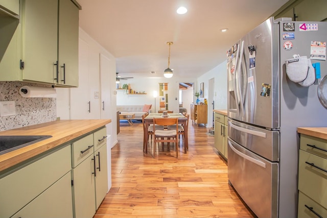 kitchen with butcher block countertops, stainless steel fridge, light wood-type flooring, and green cabinets