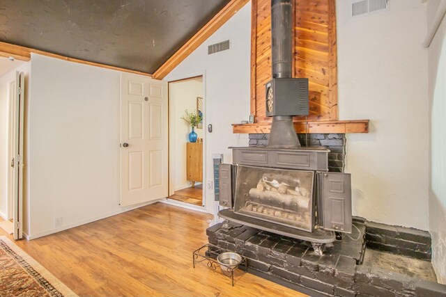 details with a wood stove, wood finished floors, and visible vents