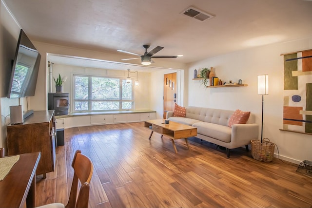 living area featuring ceiling fan, visible vents, and wood finished floors