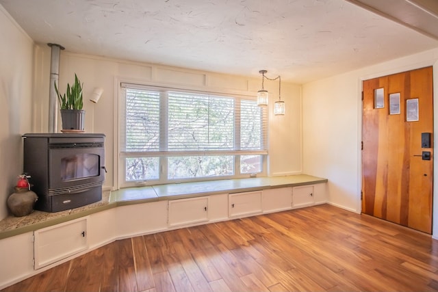 unfurnished dining area featuring light wood-type flooring and a wood stove