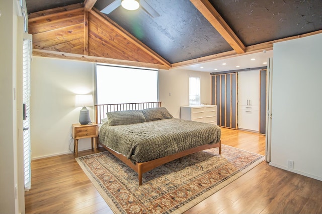 bedroom with vaulted ceiling with beams, wood finished floors, and baseboards